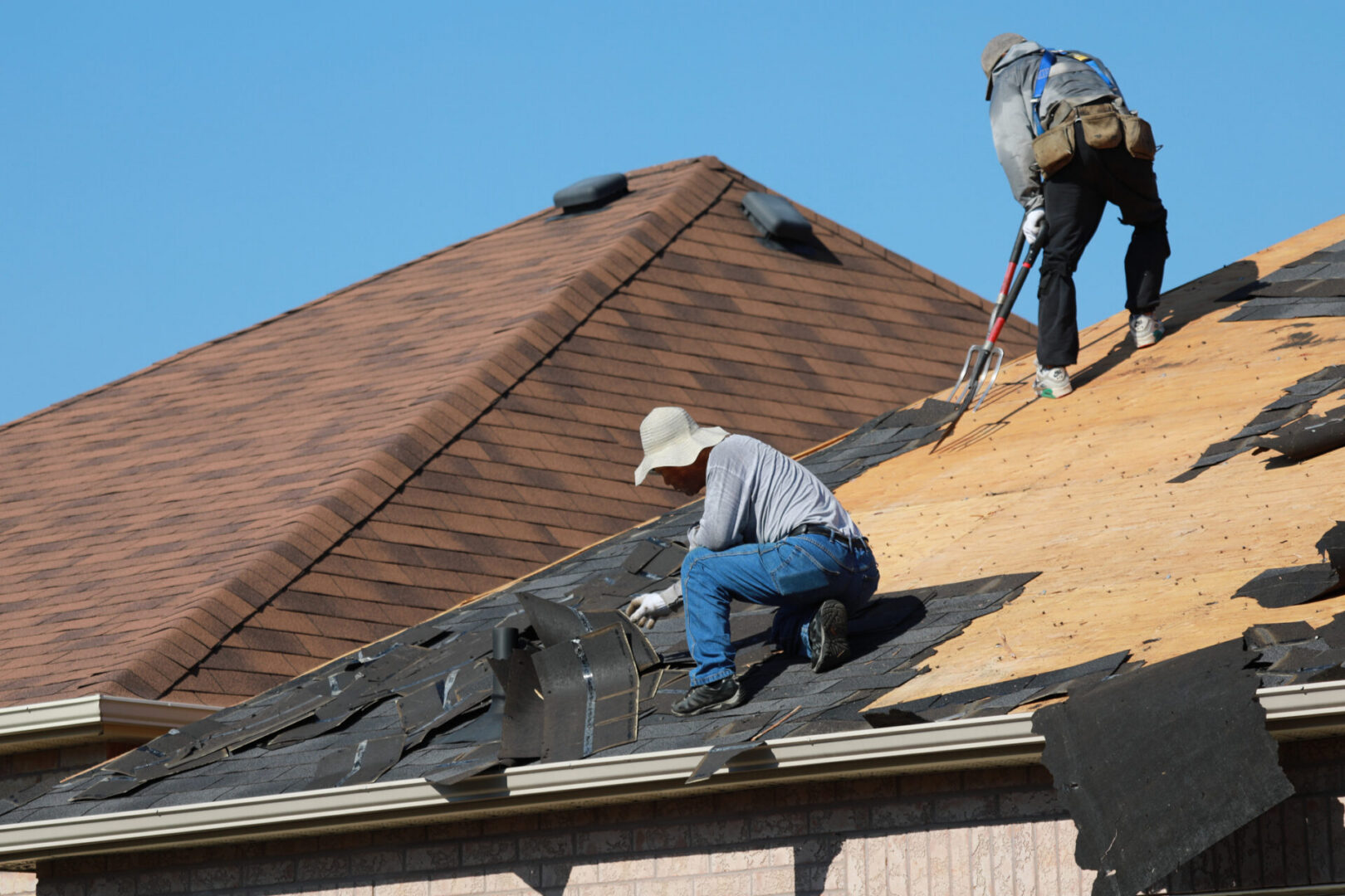 Workers repairing house roof shingles