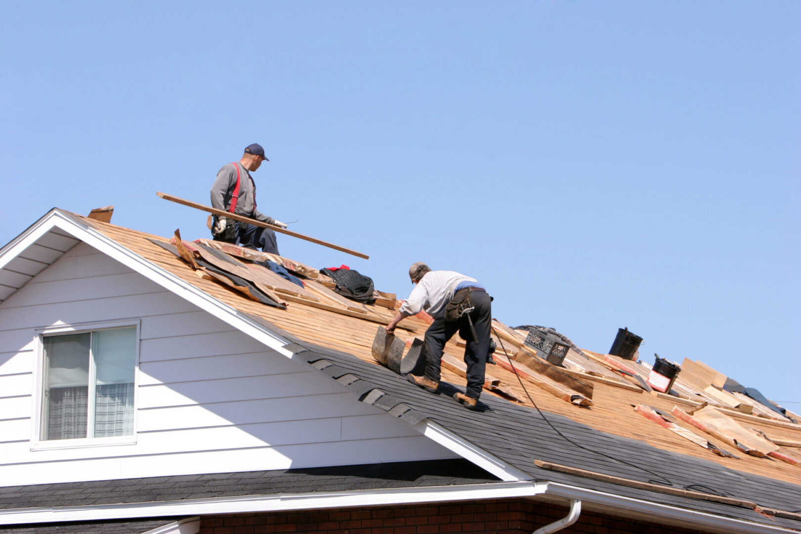 Construction workers repairing rooftop under clear sky
