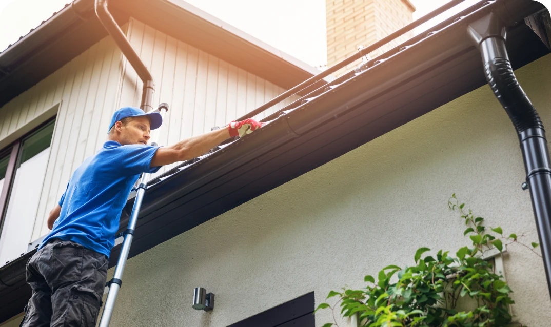 Worker maintaining roof drainage system